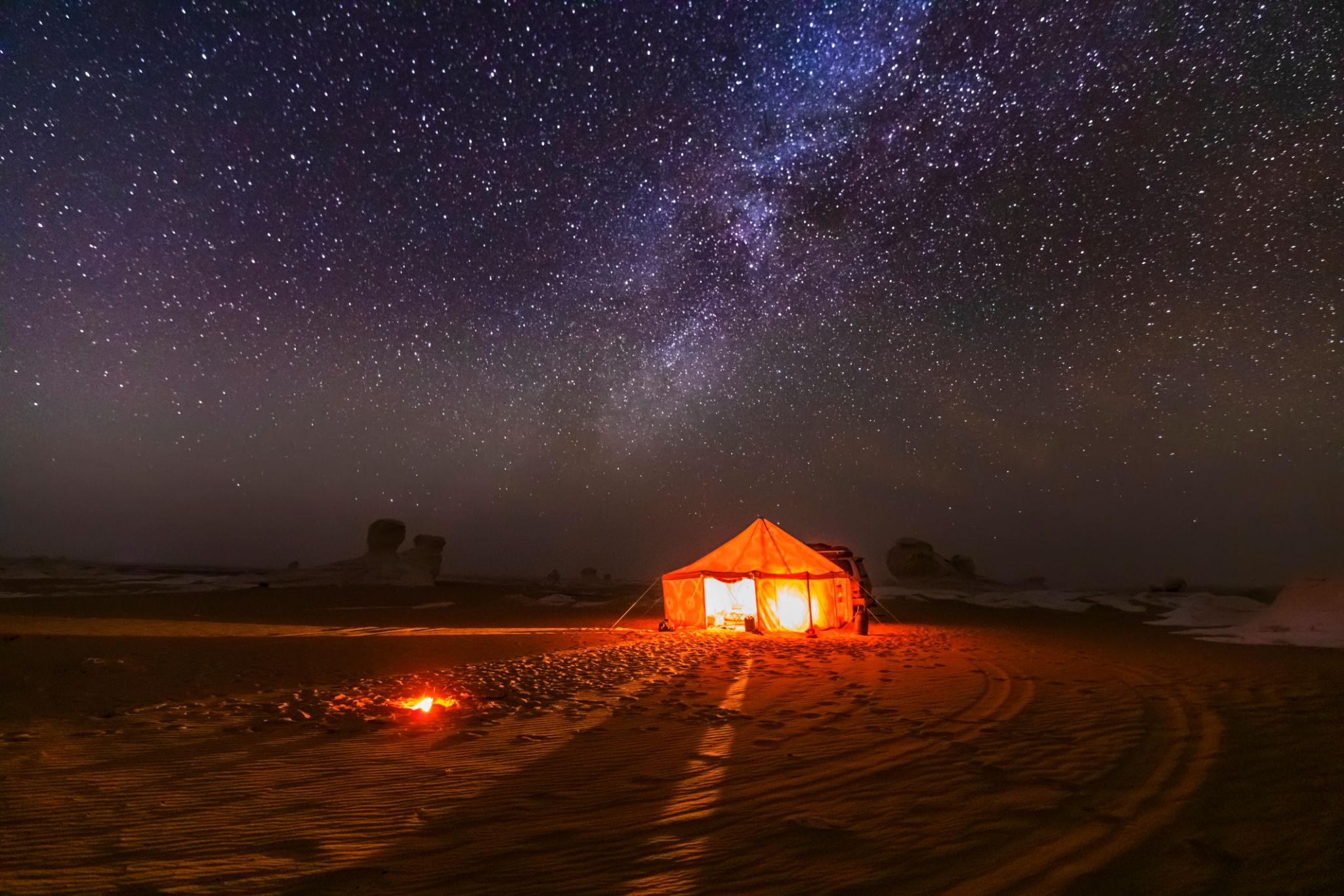 A glowing orange tent beneath the Milky Way in the White Desert of Bahariya Oasis