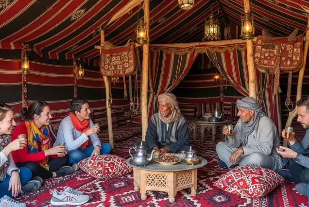 Tourists and a local host sharing tea inside a traditional decorated Bedouin tent