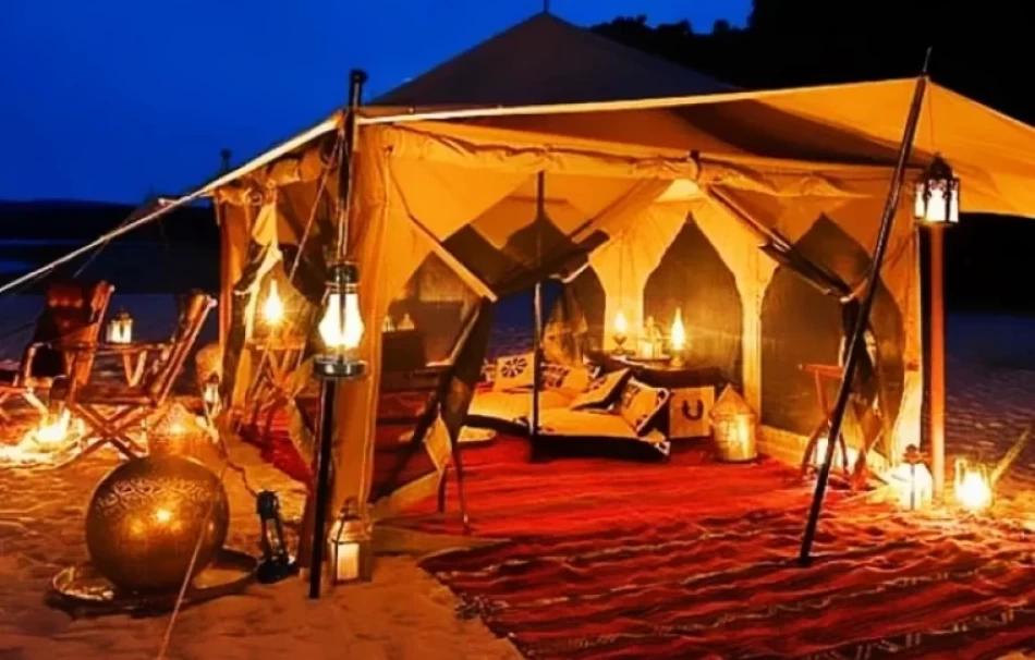 A glowing luxury Bedouin-style tent adorned with lanterns and red carpets at night