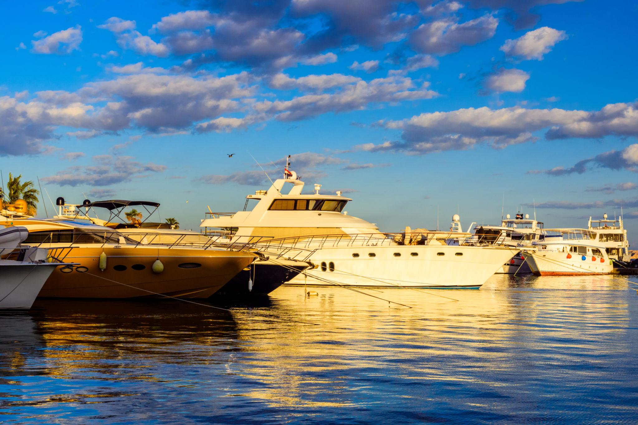 Luxury yachts moored at a Red Sea marina bathed in warm golden evening light