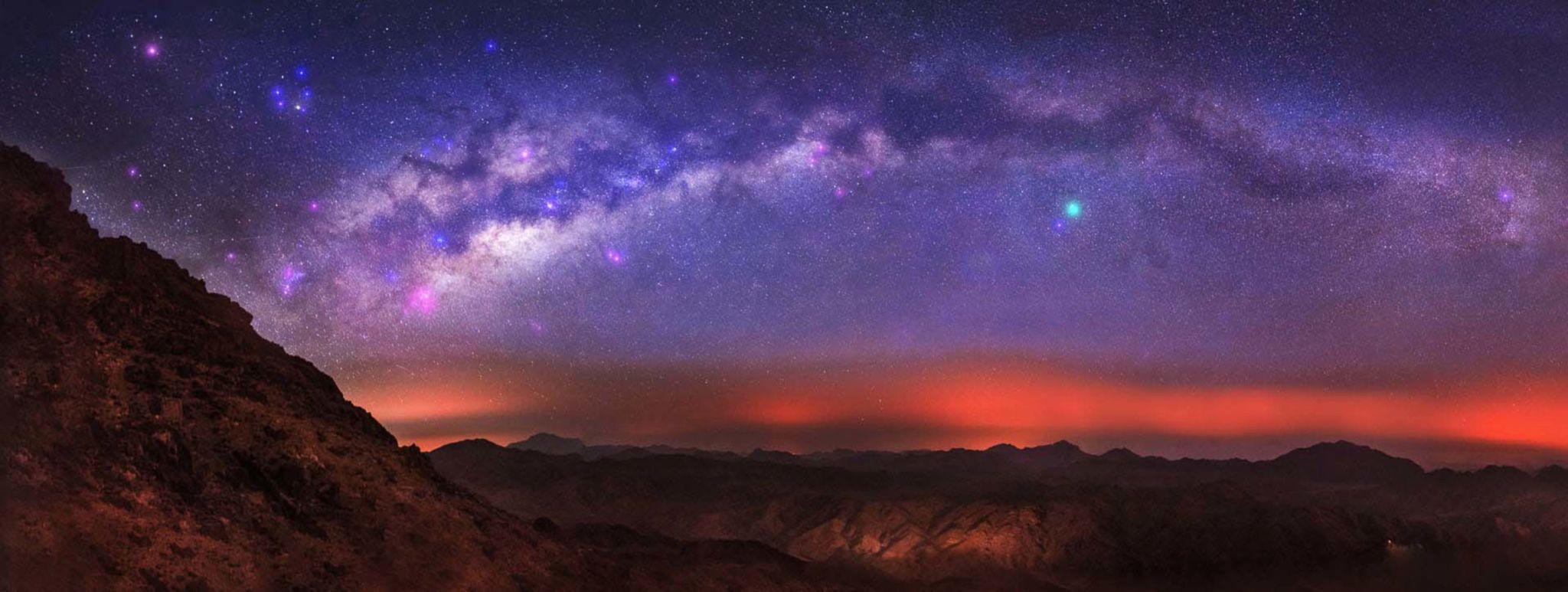 Panoramic Milky Way arc over Red Sea mountain ridges with a vivid red horizon glow