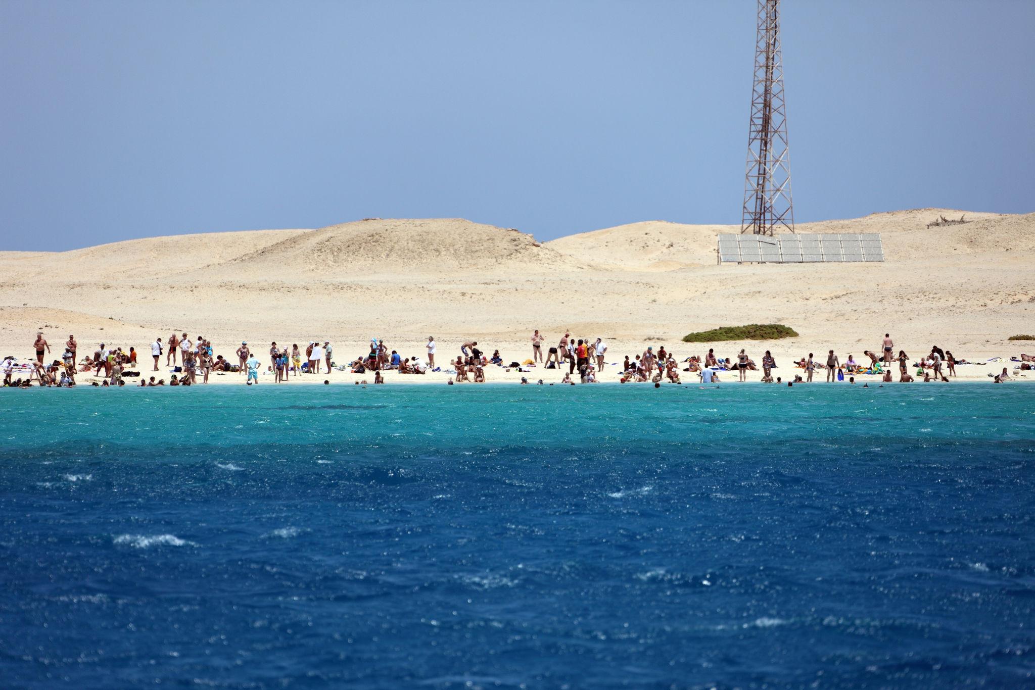 Sunbathers on sandy Red Sea island beach with turquoise water near Hurghada, Egypt