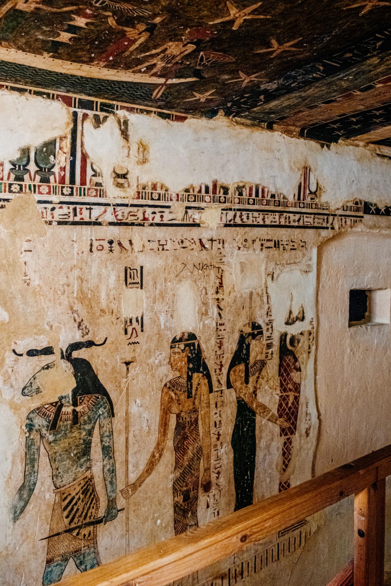 Colorful ancient Egyptian murals with hieroglyphs and deities inside a Siwa tomb