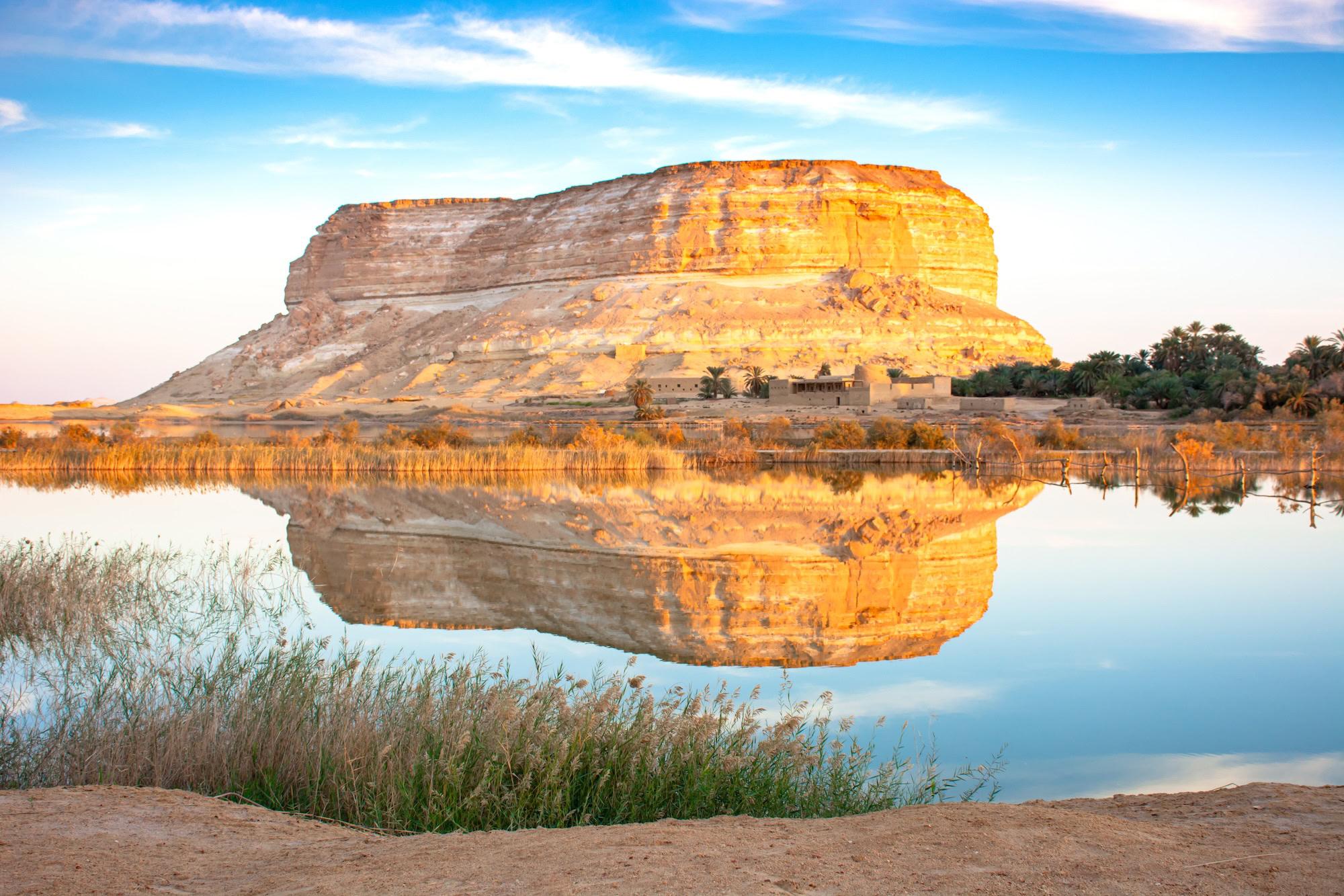 A golden sandstone mesa reflected in a still desert lake at Siwa Oasis, Egypt