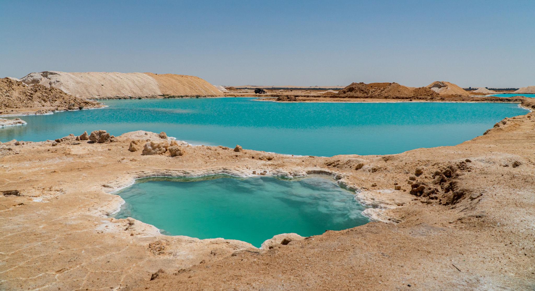 Bright turquoise salt lake pools framed by white salt crusts in Siwa