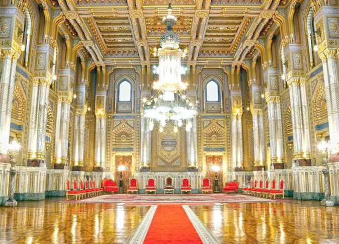 Ornate golden ceremonial hall with red velvet chairs, crystal chandeliers, and gilded columns