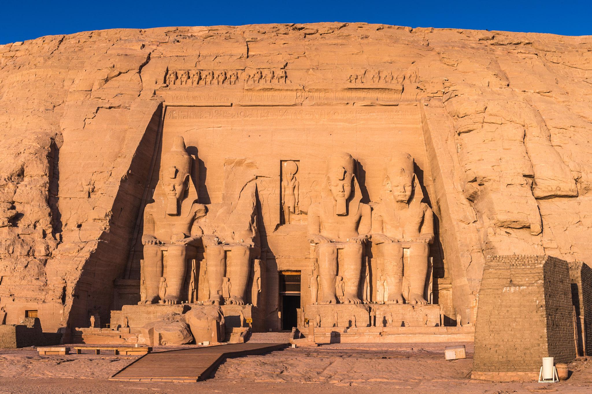 Four giant seated statues of Ramesses II carved into the sandstone facade of Abu Simbel temple.