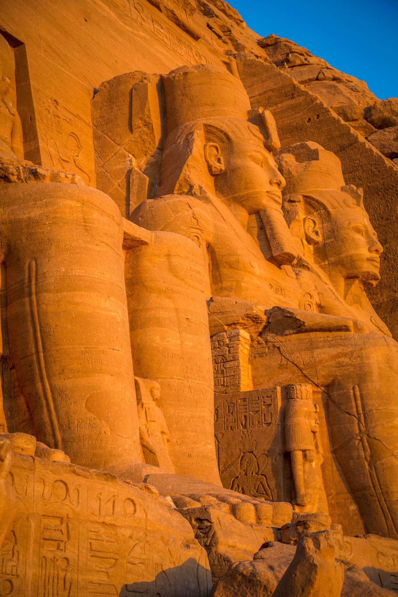 Massive sandstone colossi of Ramesses II at Abu Simbel glowing orange in warm sunlight