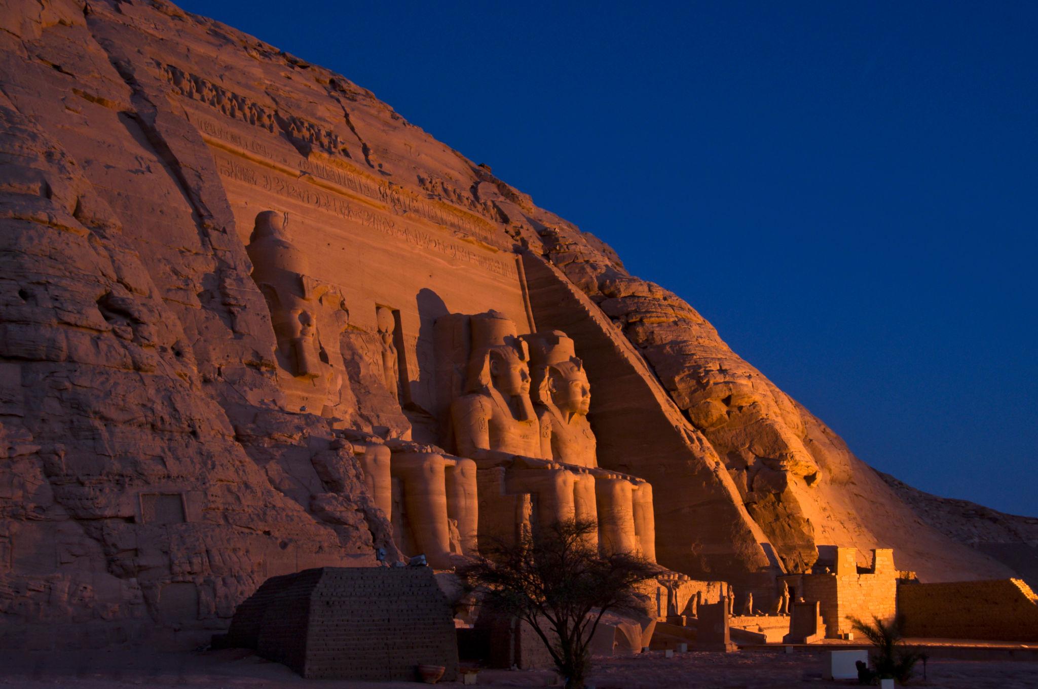 The four colossal statues of Abu Simbel temple glowing under warm lights at dusk