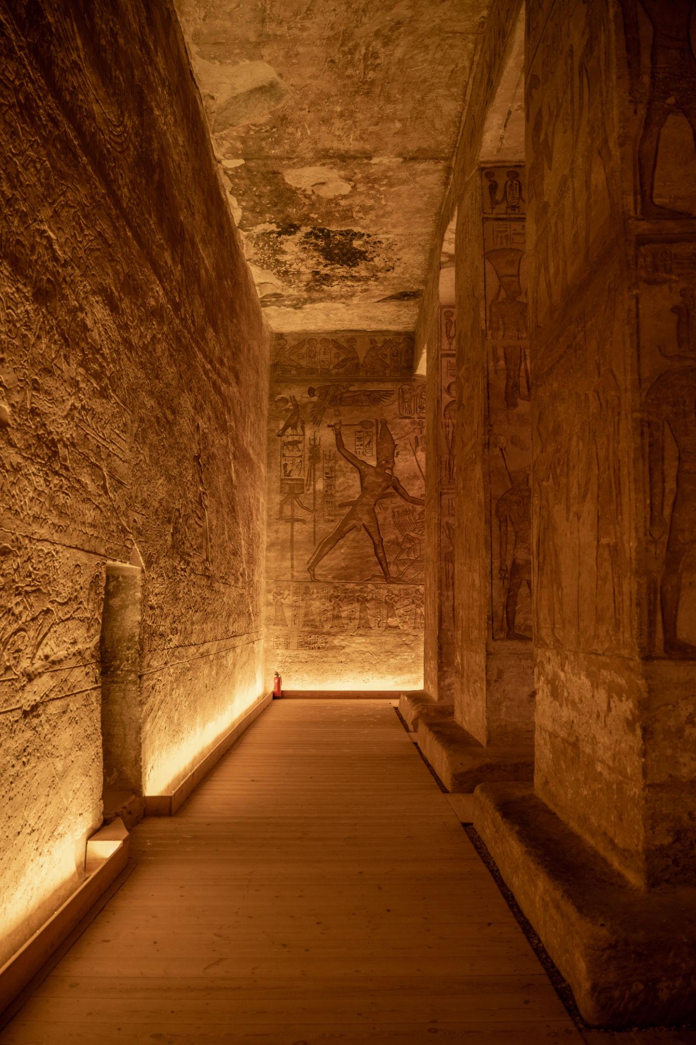 Dimly lit corridor inside Abu Simbel with ancient Egyptian relief carvings on stone walls
