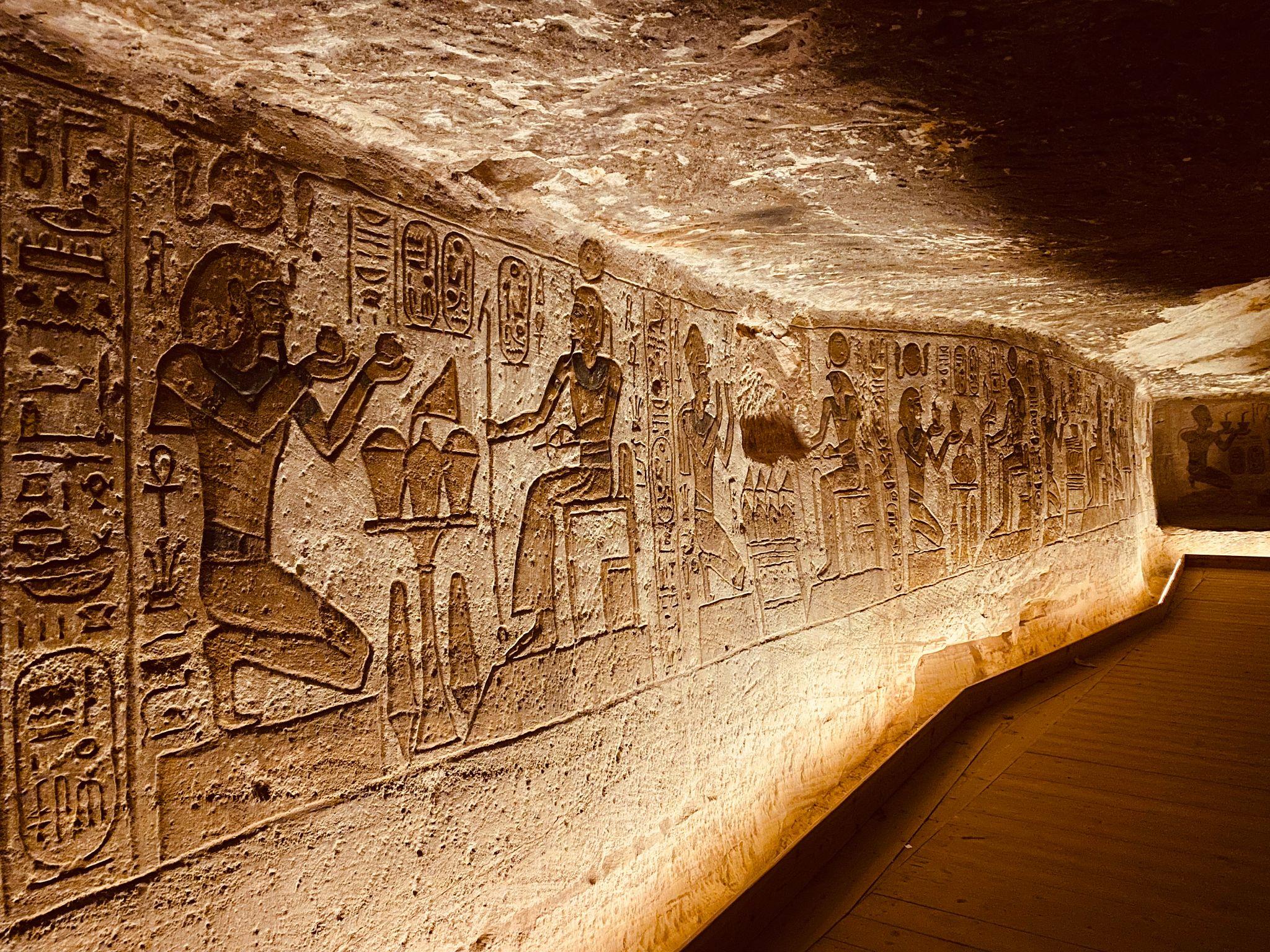 Detailed ancient Egyptian hieroglyphic carvings covering the illuminated inner walls of Abu Simbel temple