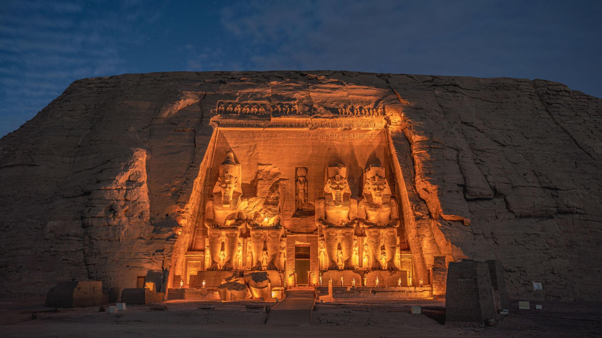 Abu Simbel temple facade dramatically lit at night with four colossal Ramesses II statues