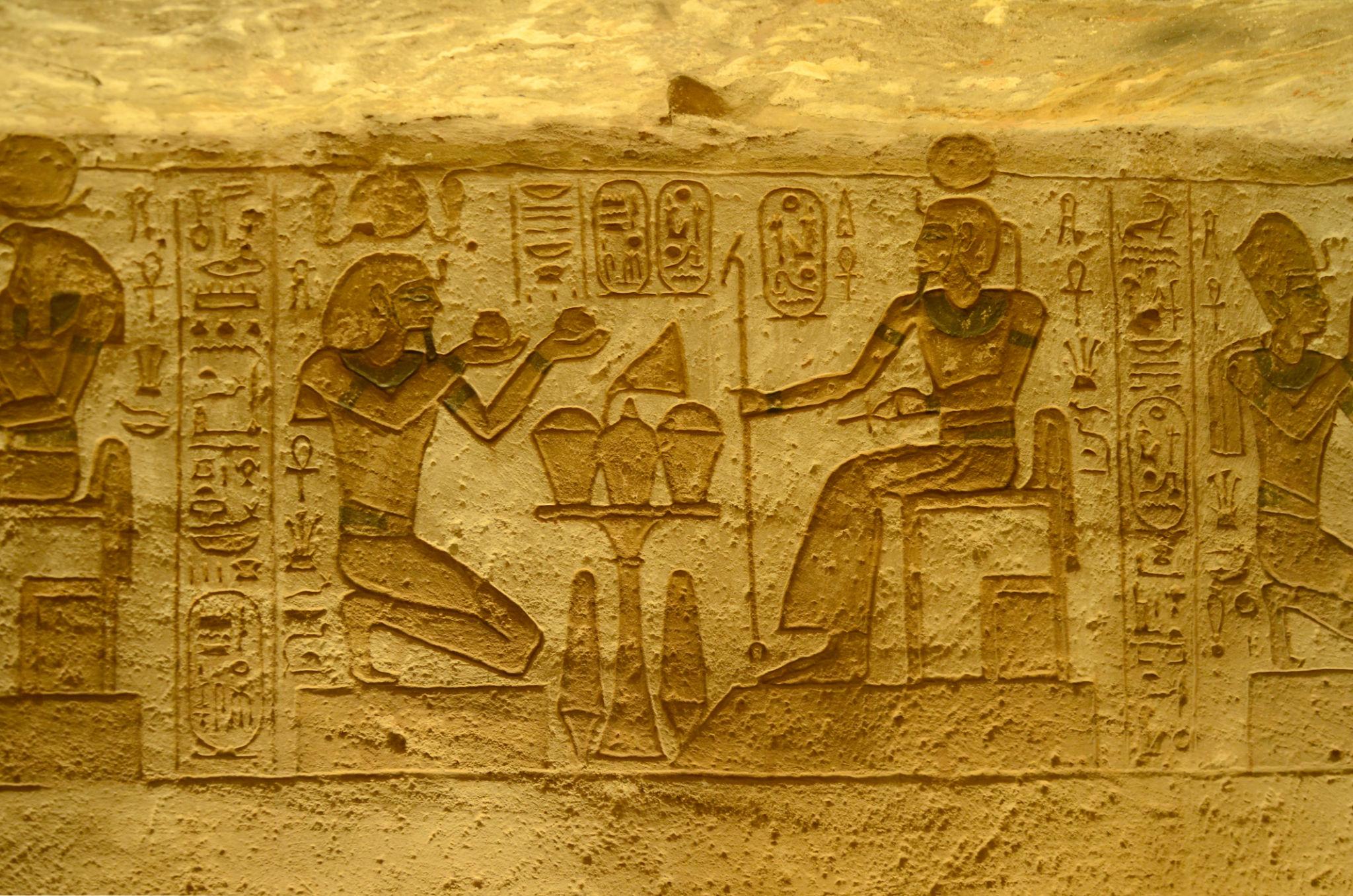 Ancient Egyptian bas-relief showing a kneeling figure making offerings to a seated deity at Abu Simbel