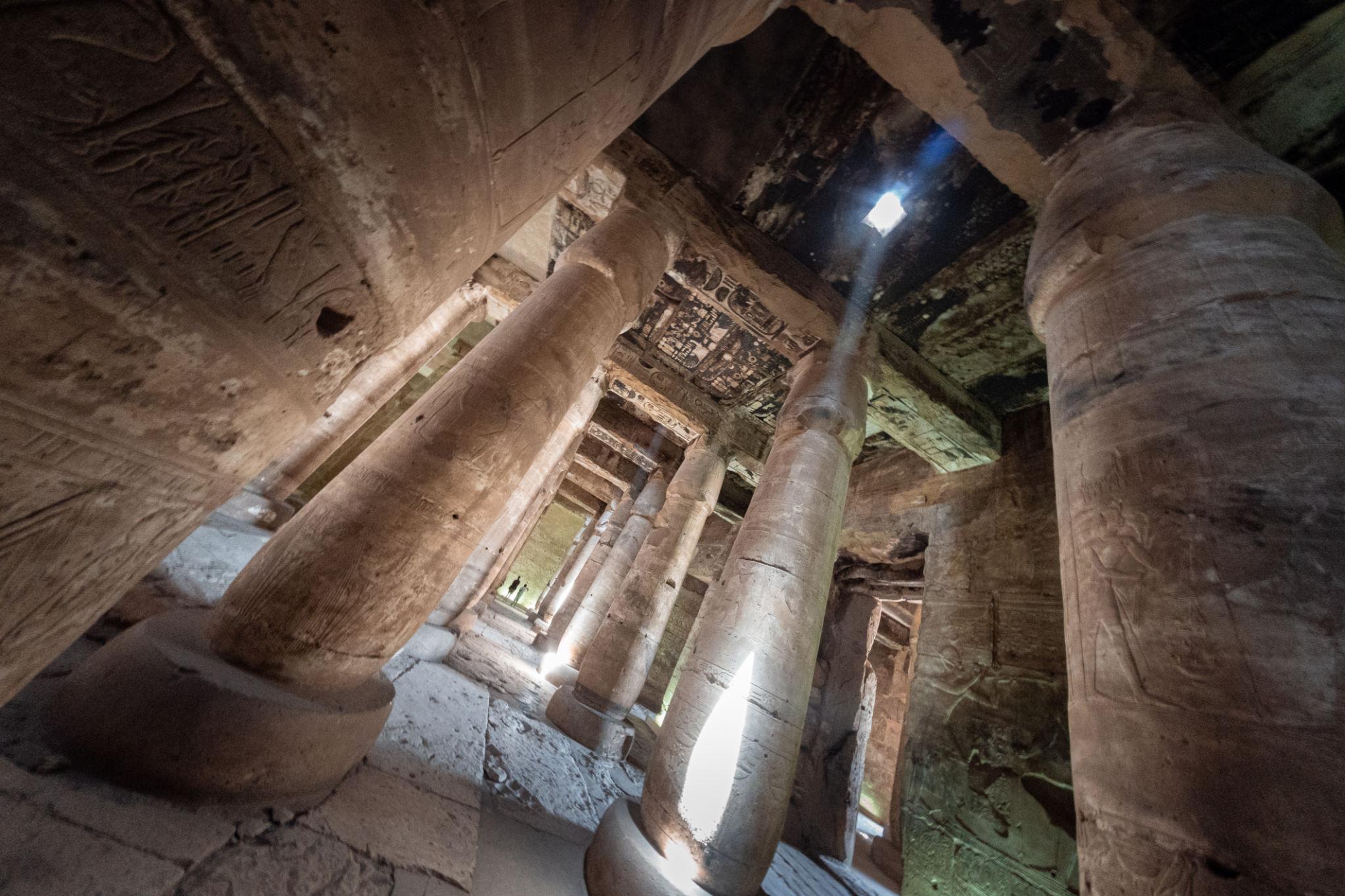Upward view of carved columns and painted ceiling inside Abydos Temple.