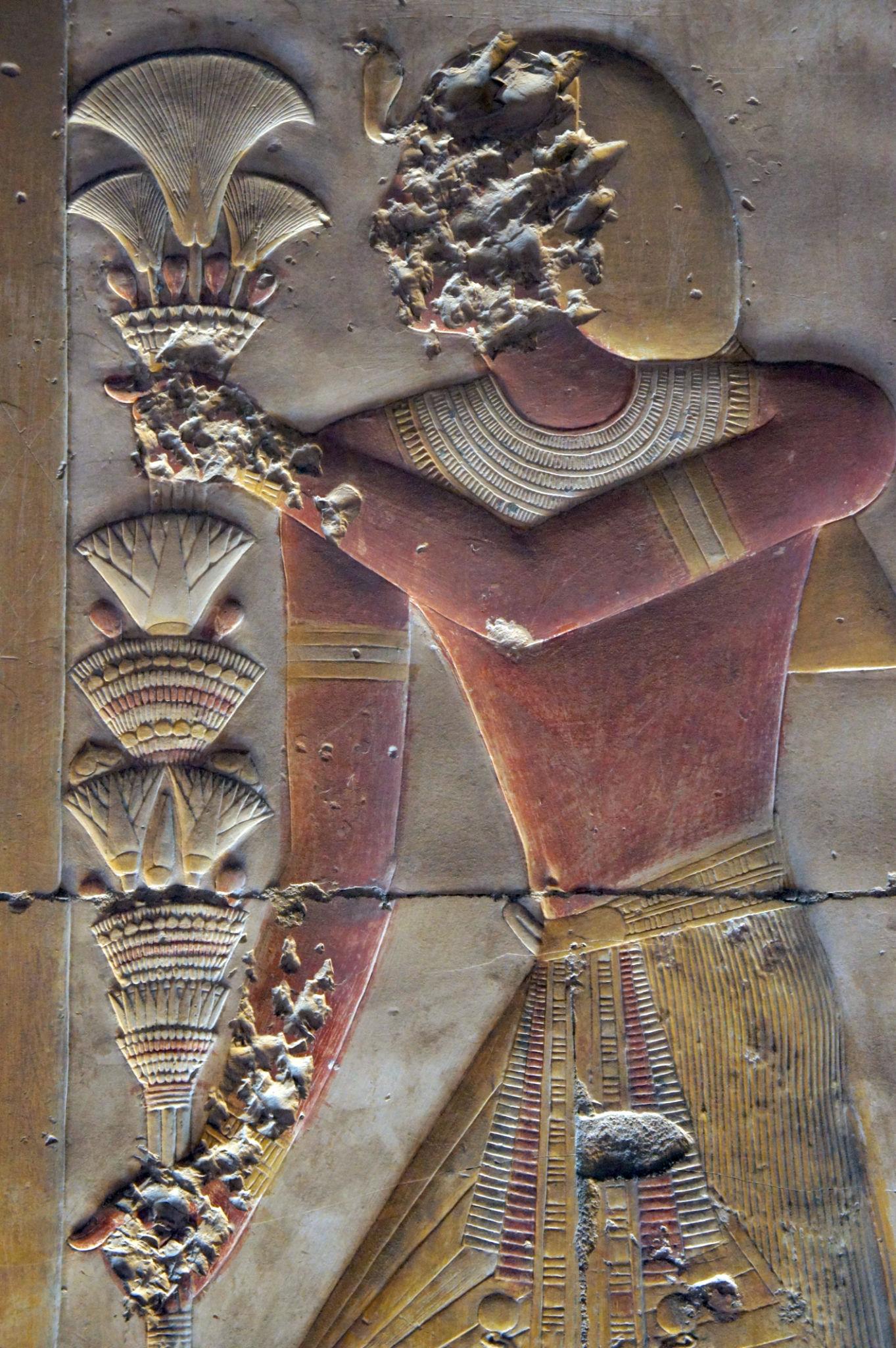 Delicate painted relief of a figure holding lotus blossoms at Abydos Temple.