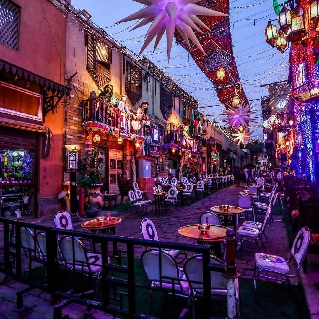 A vibrant Egyptian alley café adorned with glowing lanterns and star decorations at dusk