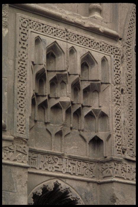 Intricate Islamic muqarnas and geometric carvings on a historic stone wall facade