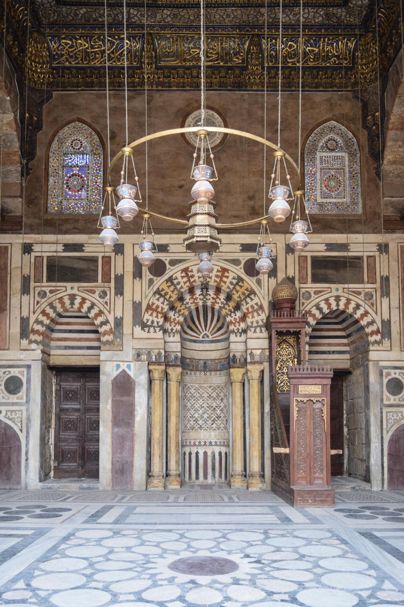 Elaborately decorated mihrab niche and wooden minbar pulpit inside a historic Cairo mosque