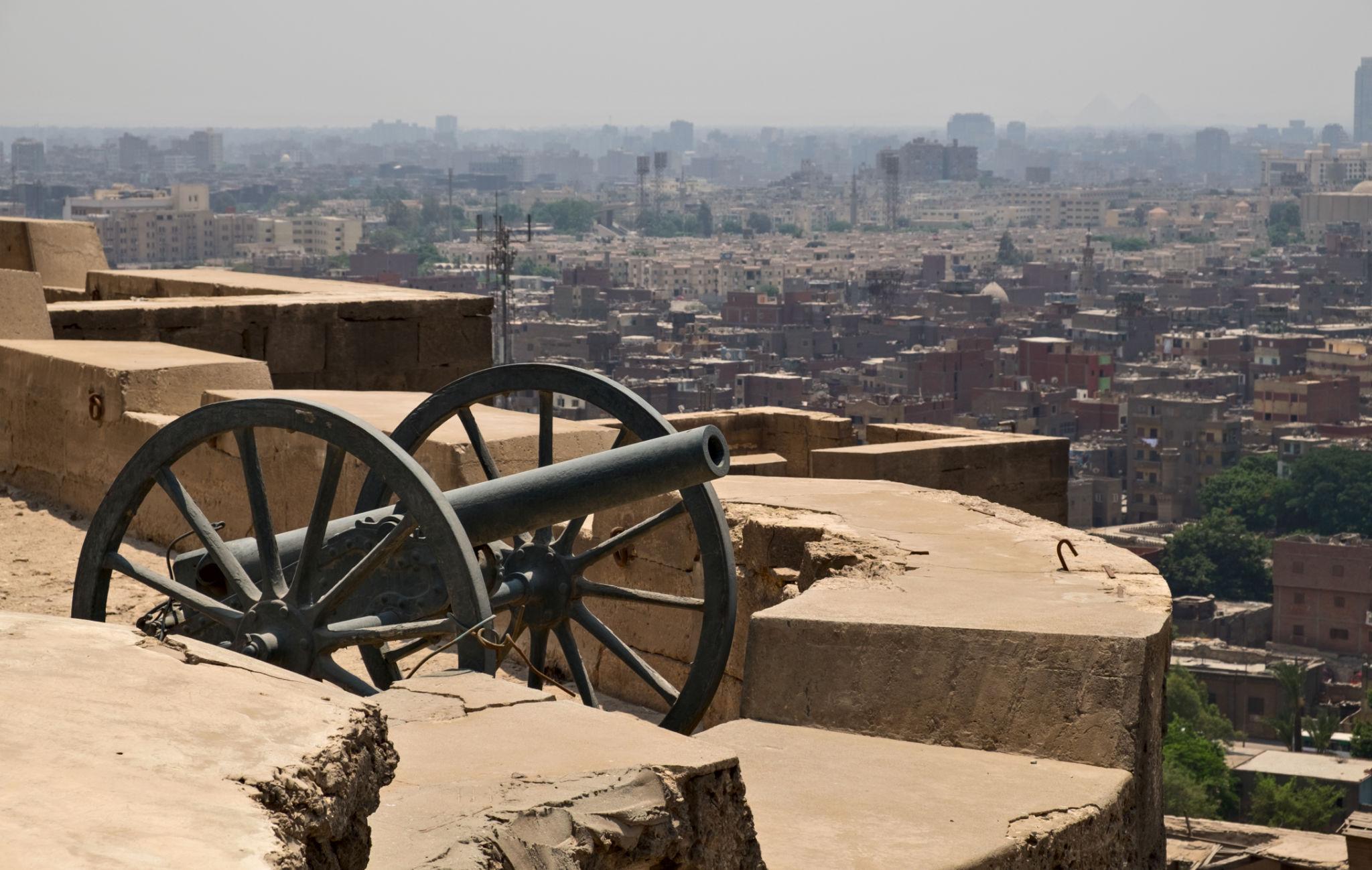 Historic cannon on Citadel ramparts overlooking Cairo with the pyramids faintly on the horizon