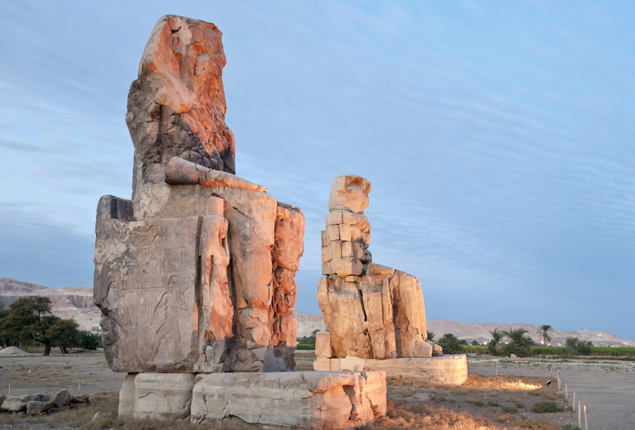 Side view of the two Colossi of Memnon statues in soft evening light near Luxor