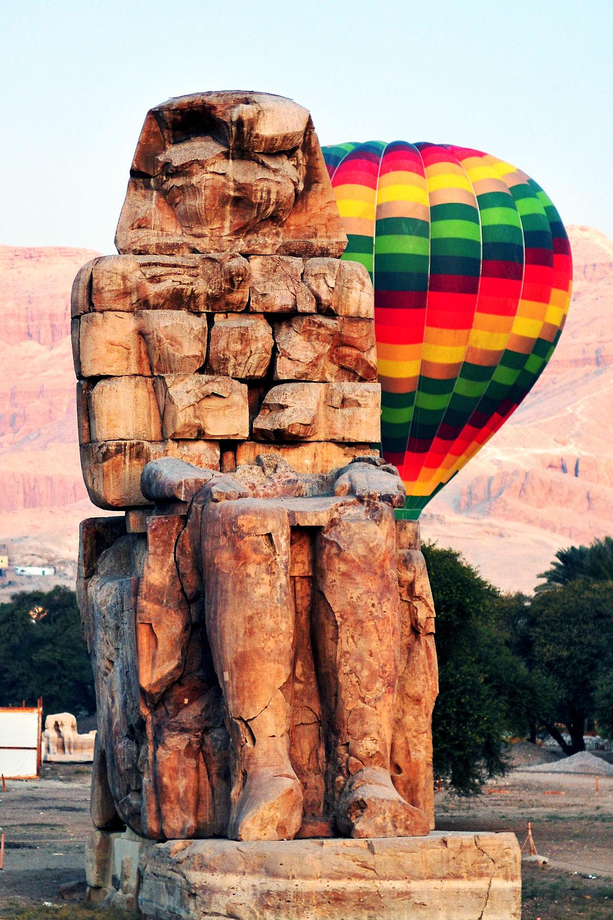 Colorful hot air balloon beside a Colossus of Memnon on the Luxor west bank