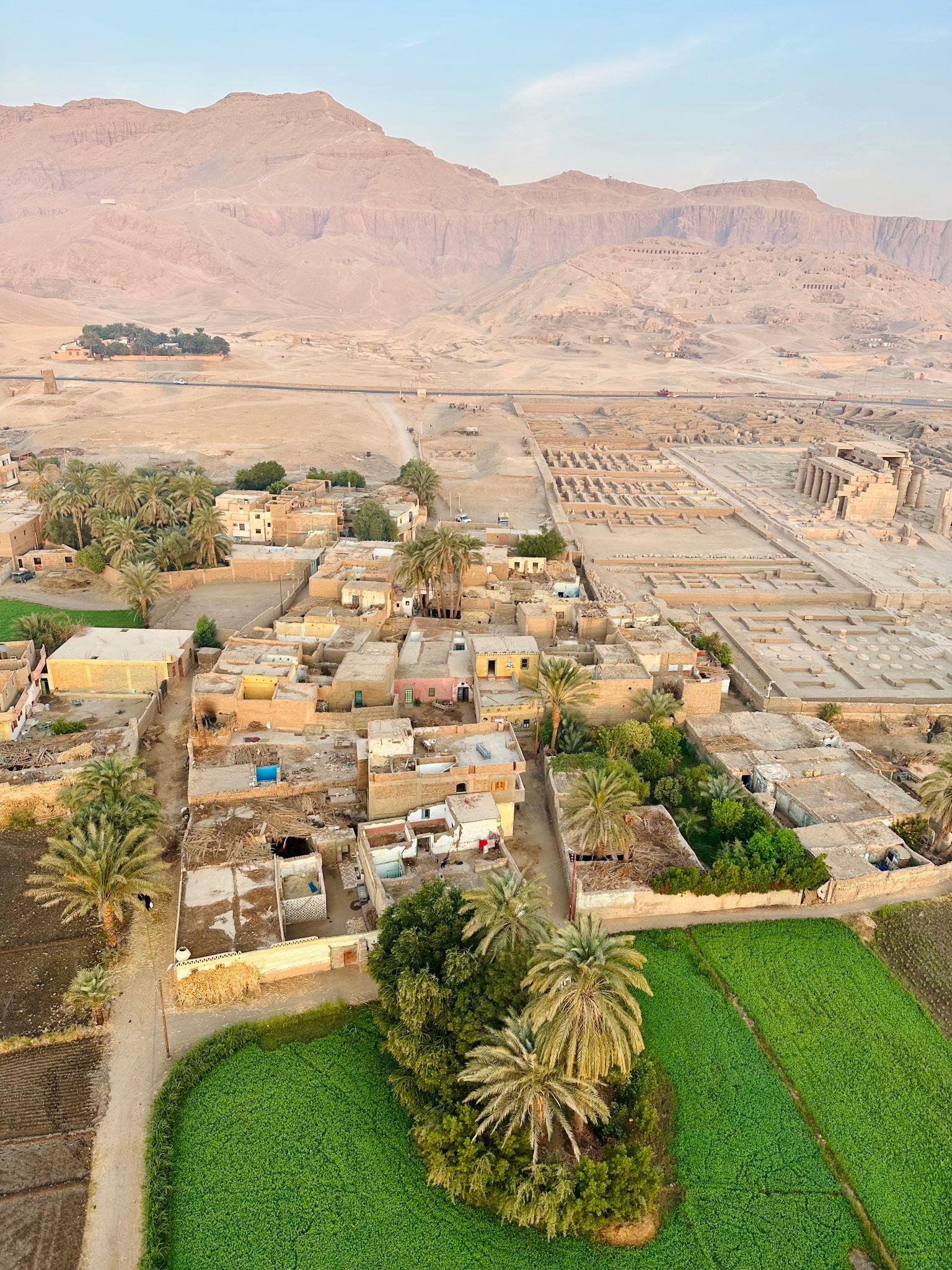 Aerial view of Deir el-Medina village nestled between palm groves and the Theban mountains