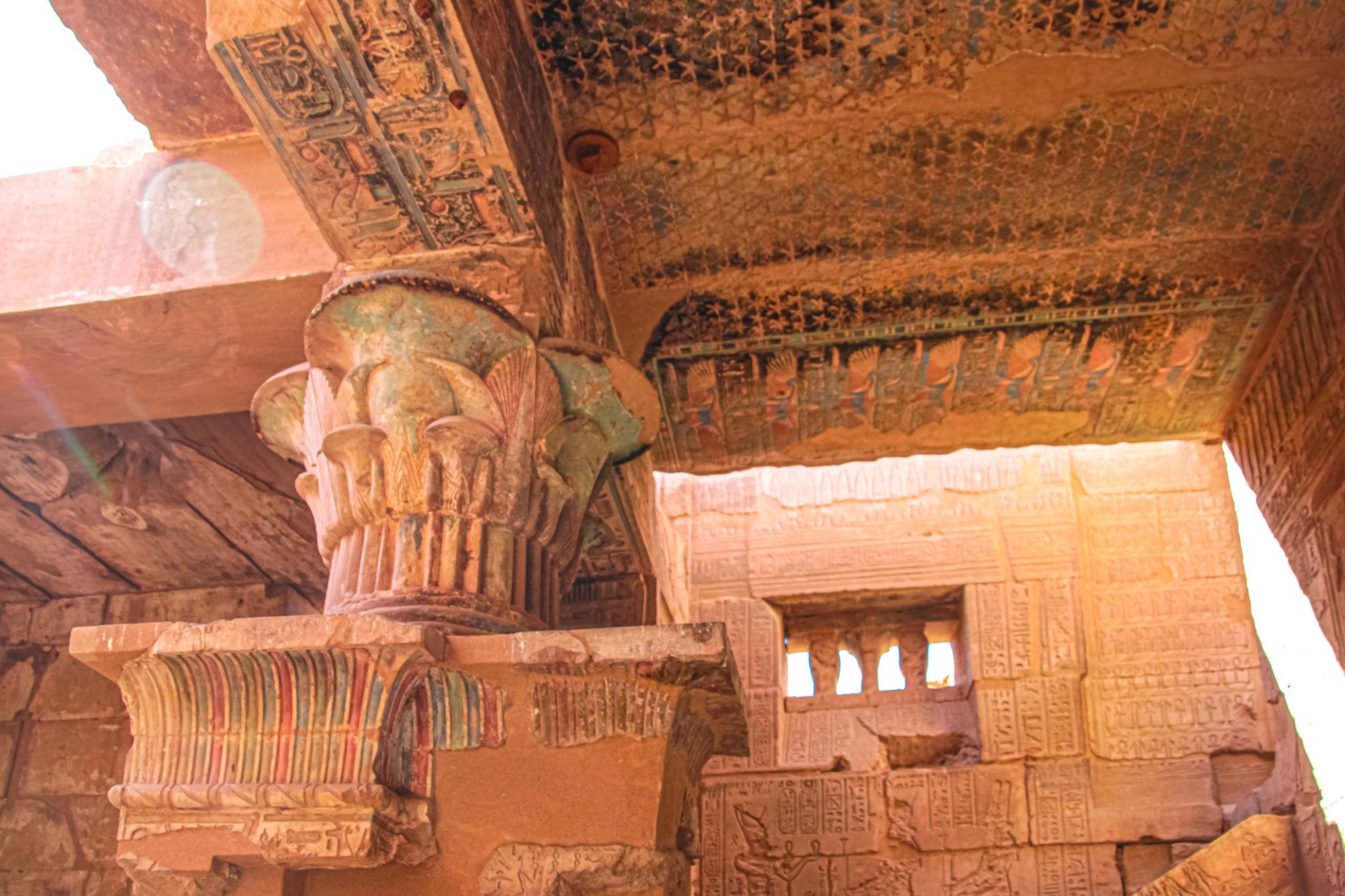 Detail of painted Hathor column capital and decorated ceiling inside the Deir el-Medina temple