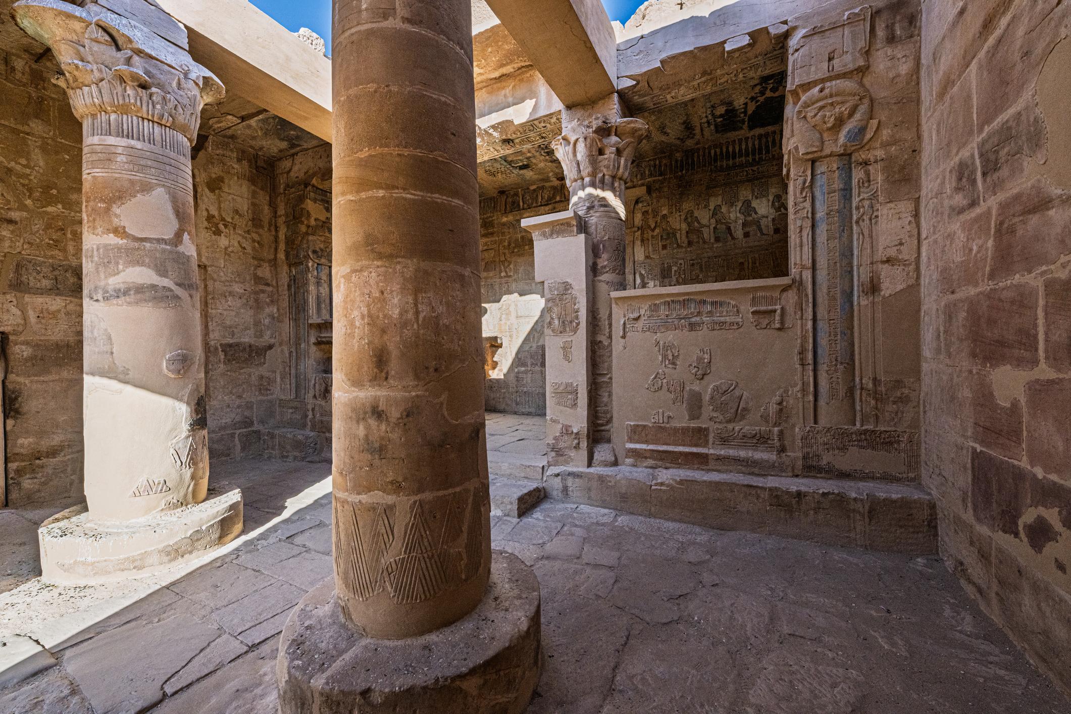 Sunlit pillared court of the Ptolemaic Hathor temple at Deir el-Medina with carved reliefs