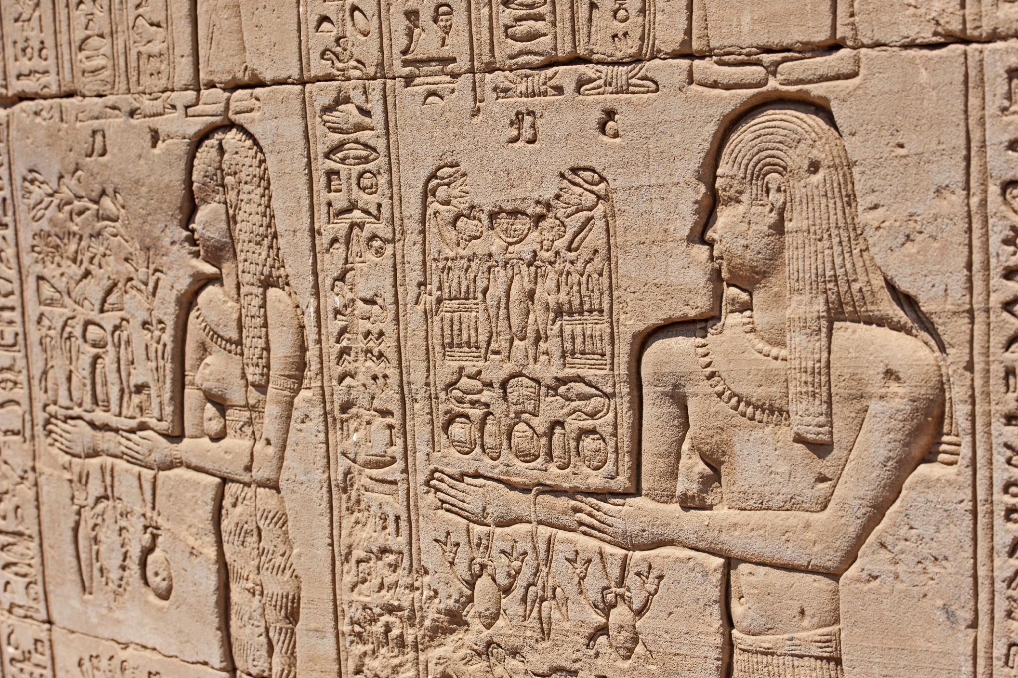 Delicate wall relief of Ptolemaic queens making offerings carved in soft sandstone.