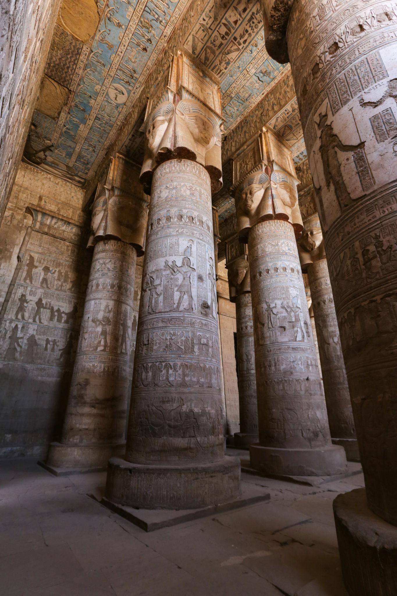 Gallery of towering carved columns filling the hypostyle hall of Dendera Temple.