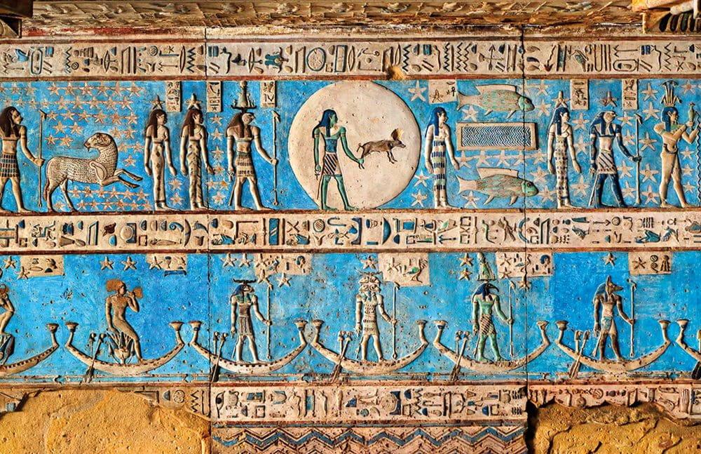 Vibrant blue ceiling panel with lunar disc and celestial barques at Dendera Temple.