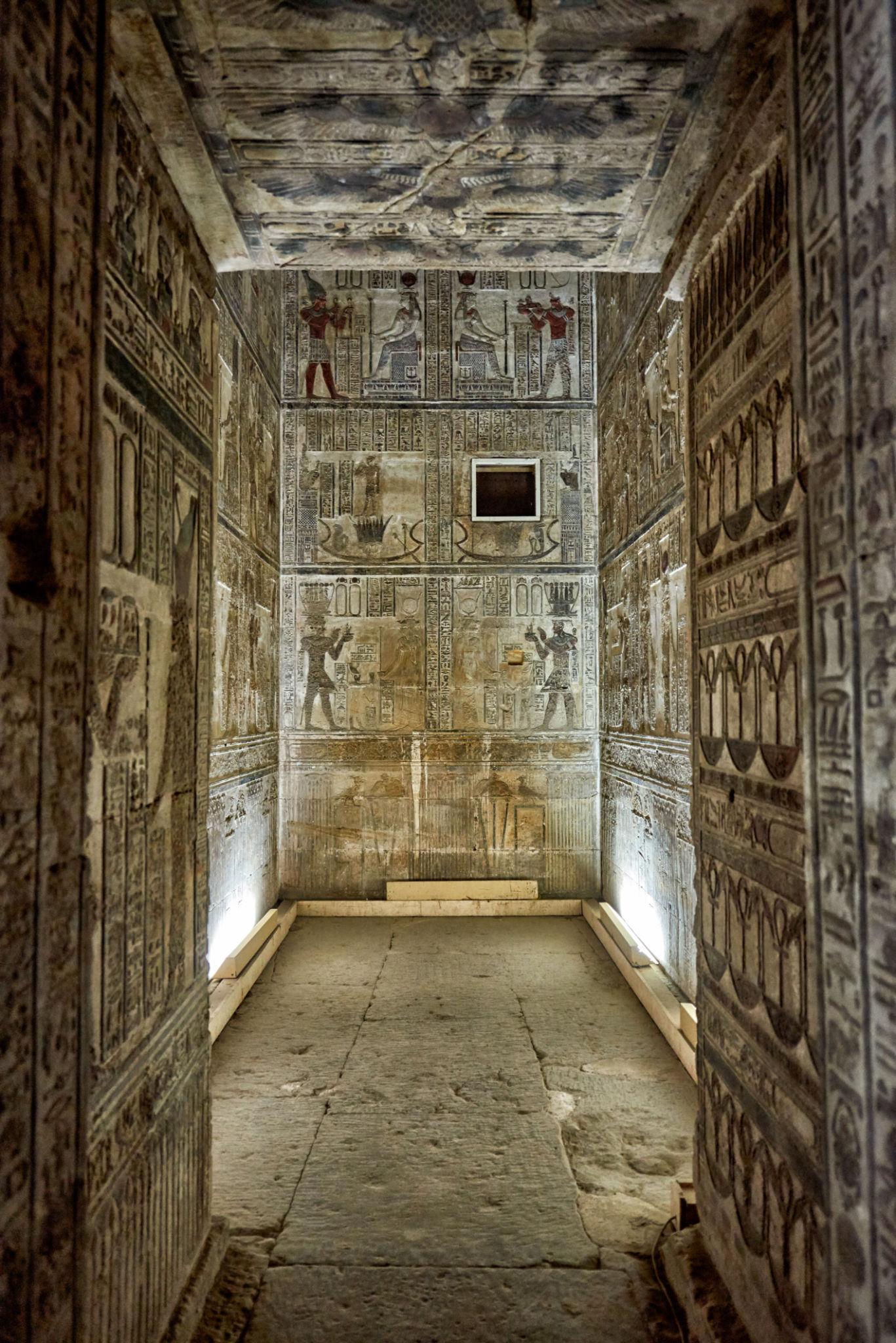 Narrow painted corridor with hieroglyph-covered walls and astronomical ceiling inside Dendera.