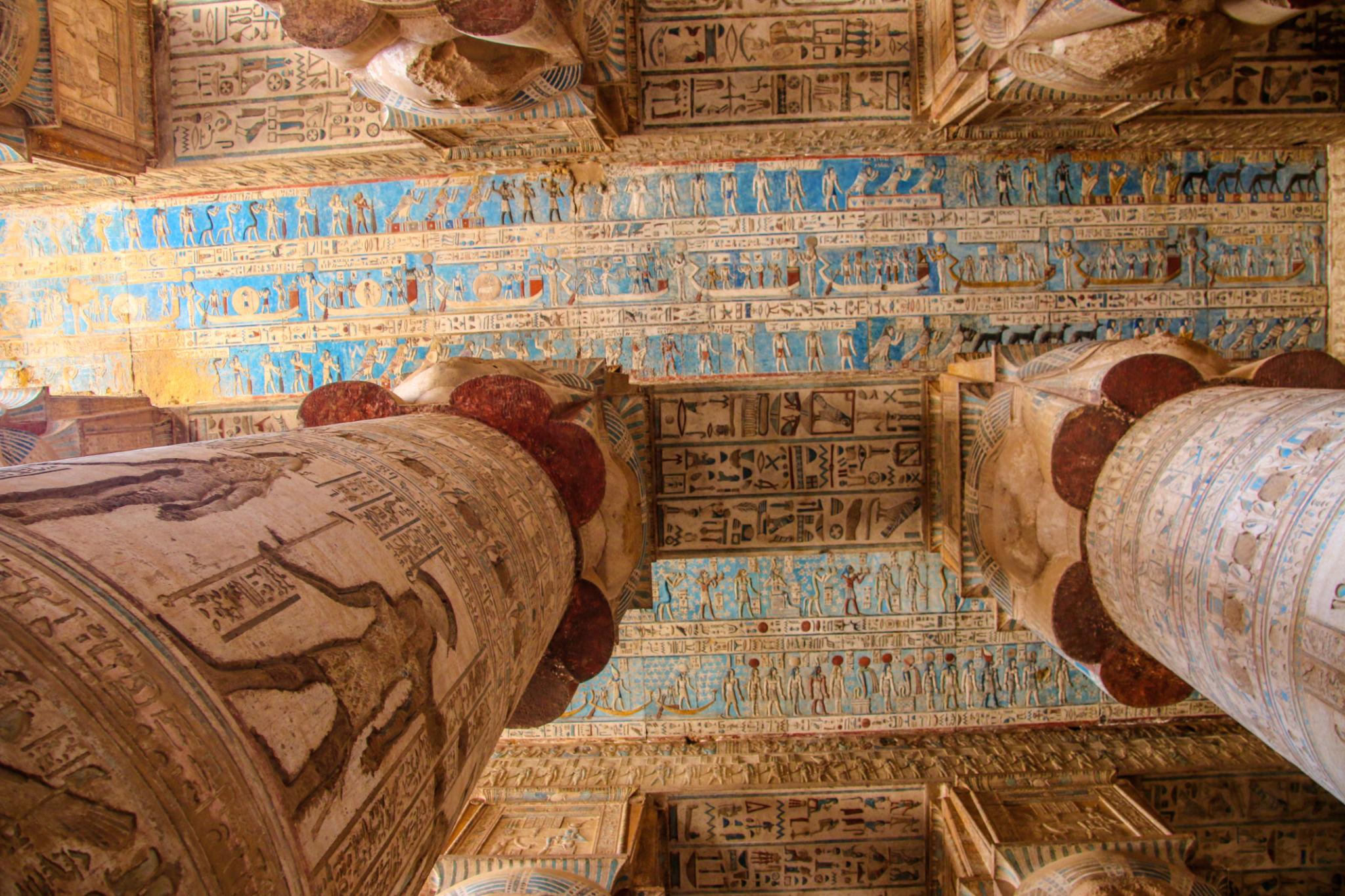 Ornate blue-and-gold ceiling with vulture frieze between massive Hathor columns.