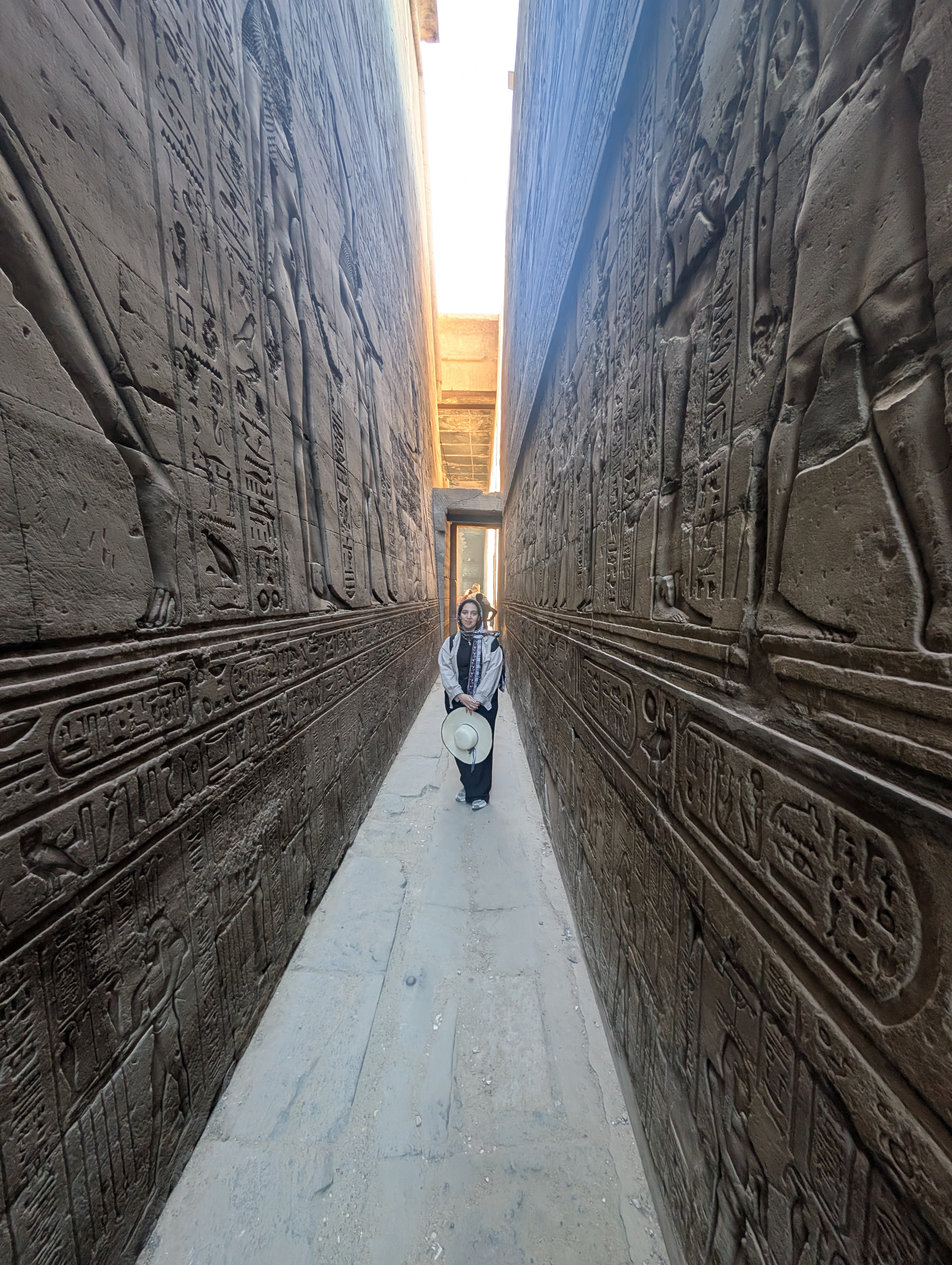 Visitor standing in the narrow ambulatory corridor of the Temple of Edfu.