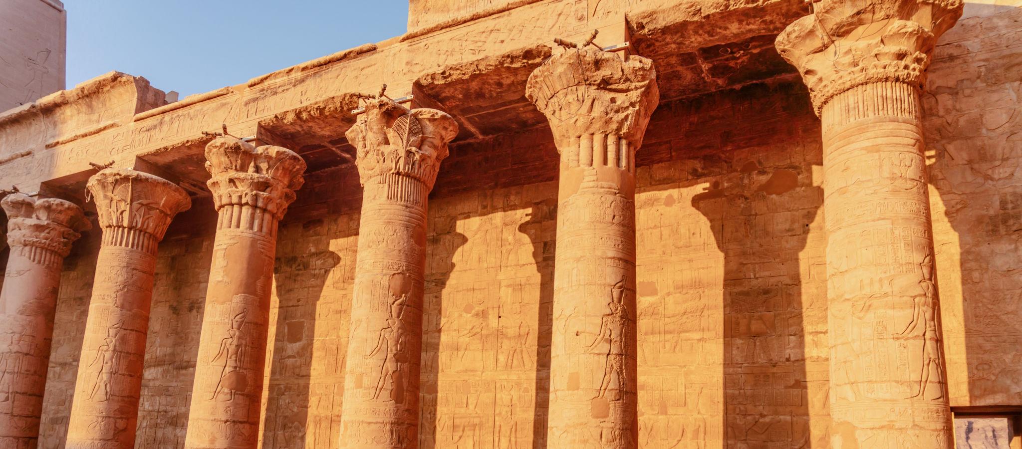 Golden sunset light on the exterior colonnade of the Temple of Edfu.