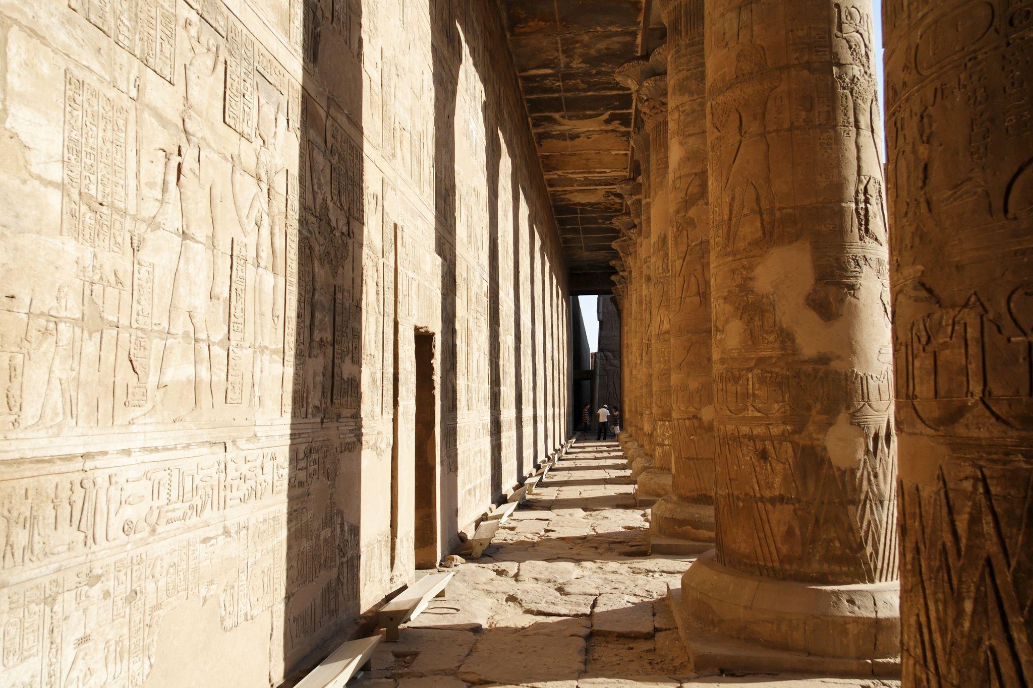 Sunlit colonnade walkway between carved walls at the Temple of Edfu.
