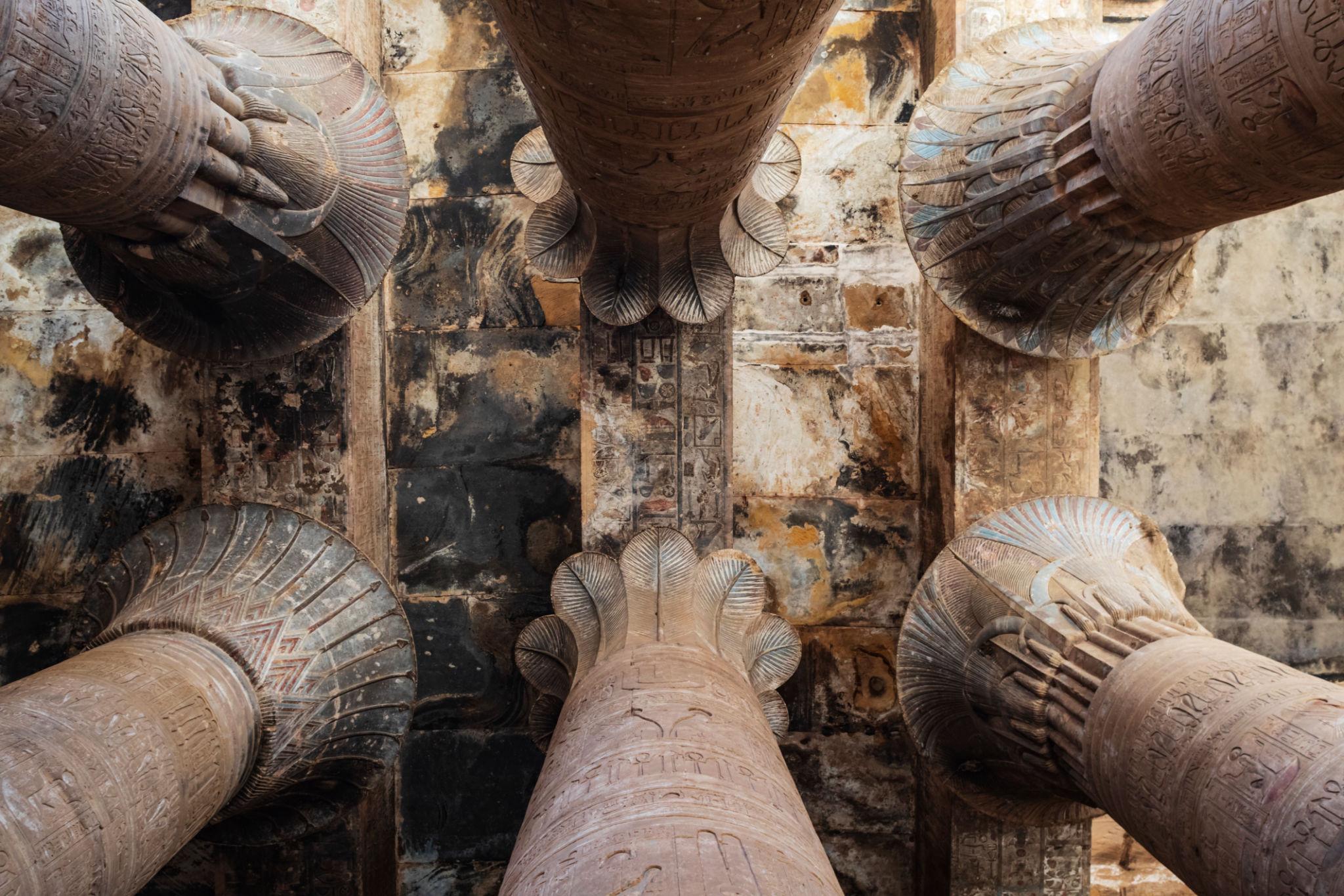 Upward view of ornate column capitals and ceiling inside the Temple of Edfu.