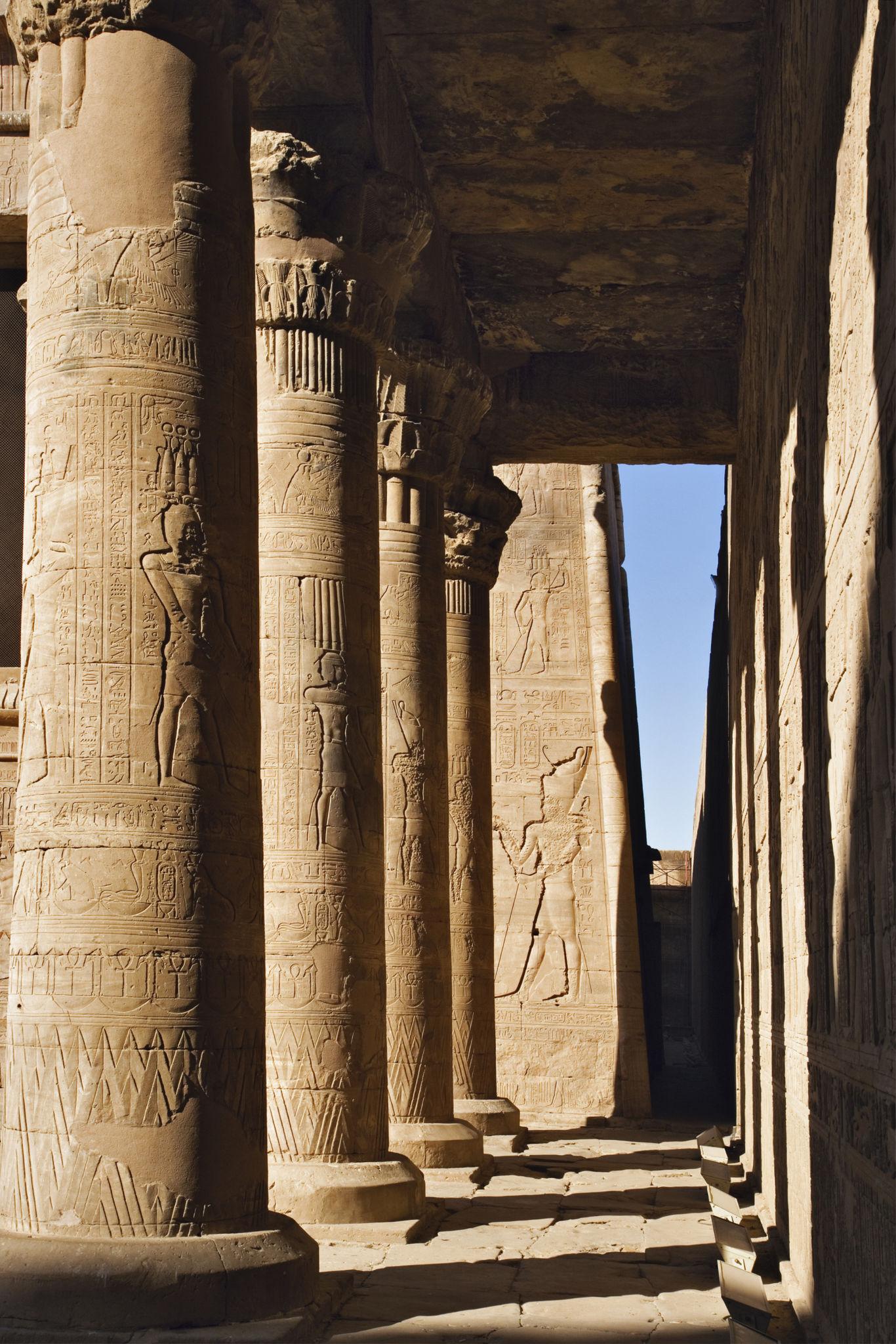 Row of carved sandstone columns casting sharp shadows at the Temple of Edfu.