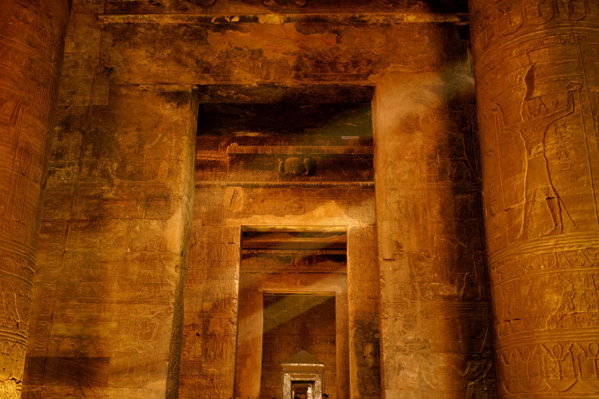 Warm-lit stone gateway leading deeper into the halls of the Temple of Edfu.