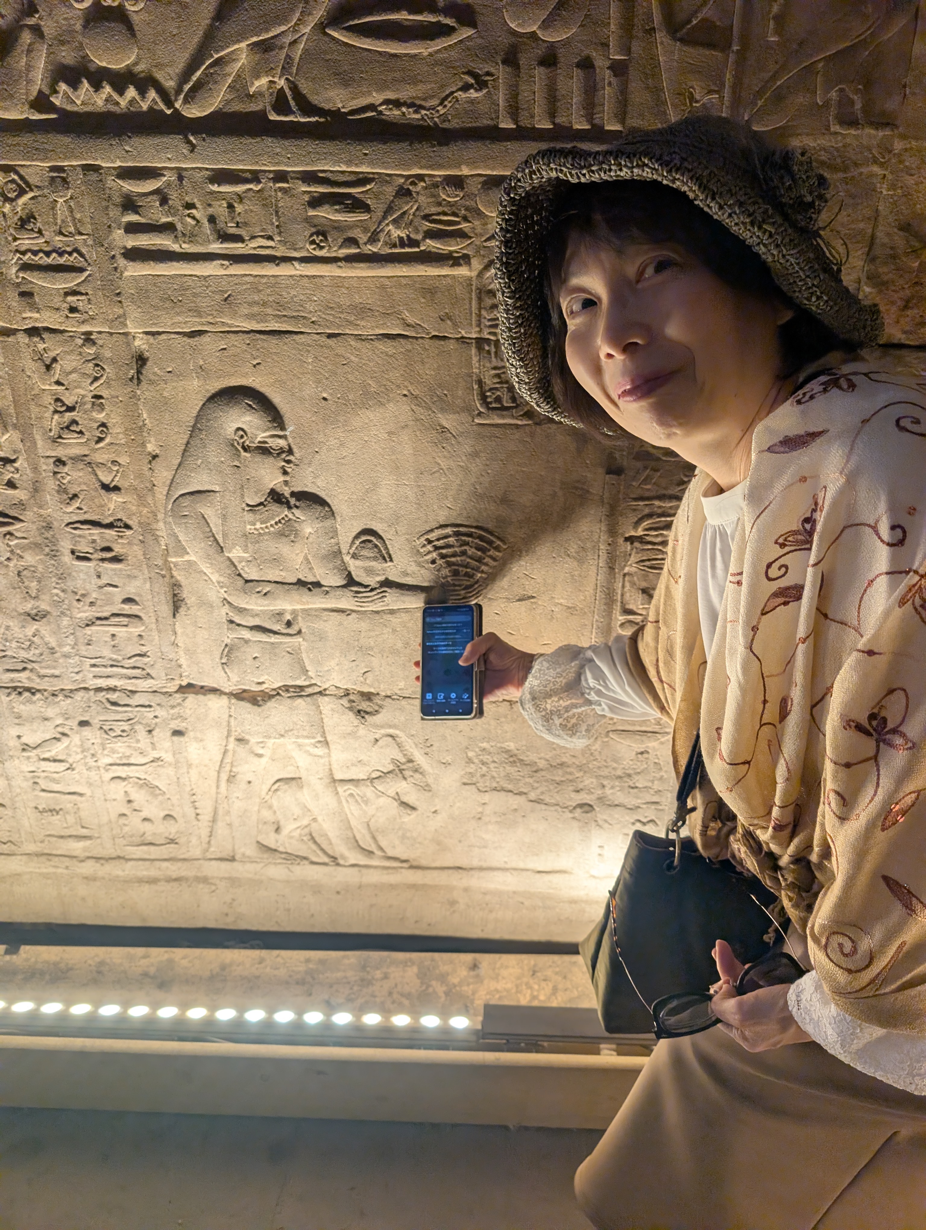 Visitor reading guide notes beside a carved relief inside the Temple of Edfu.