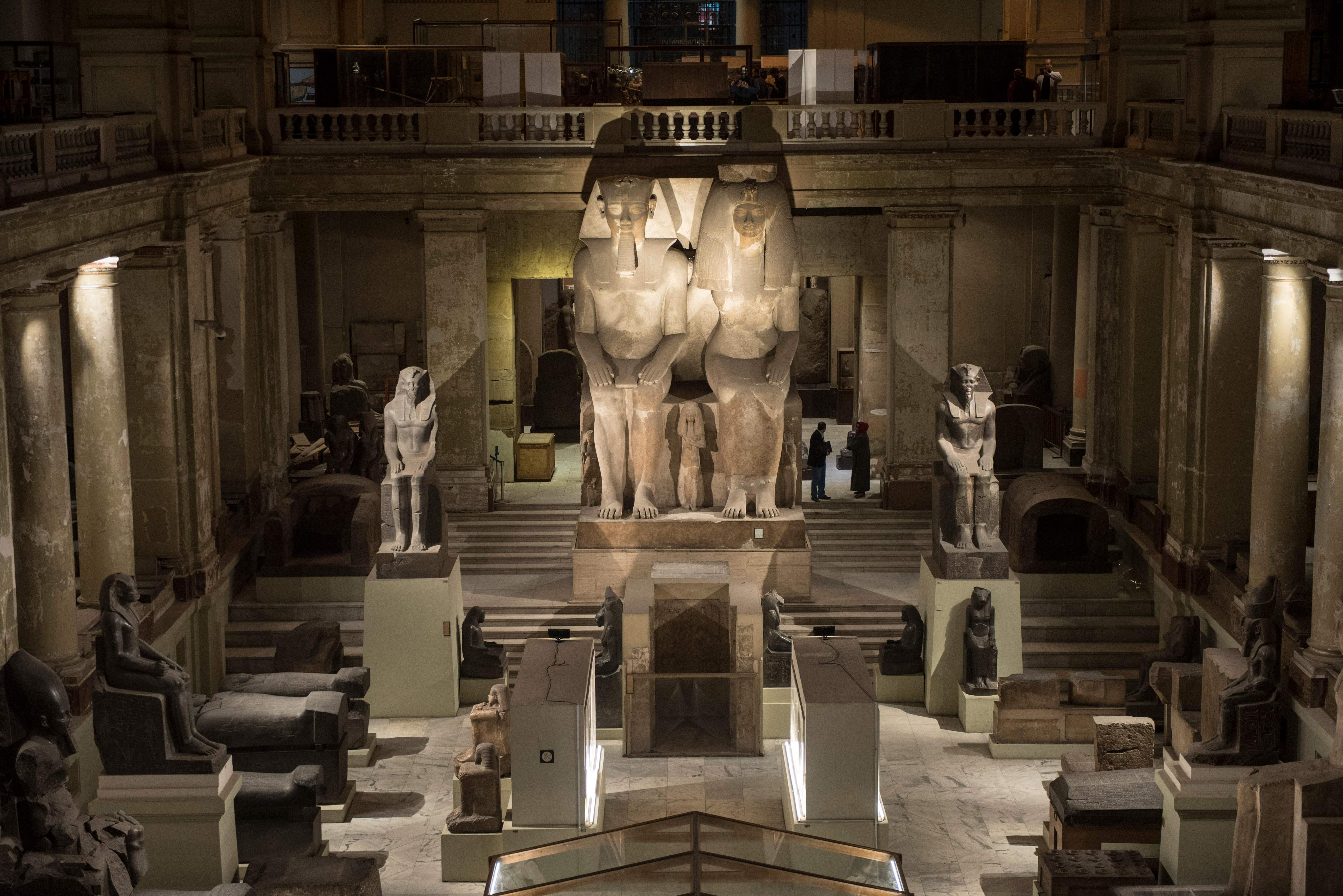 Grand hall of the Egyptian Museum displaying colossal pharaoh statues under warm lighting
