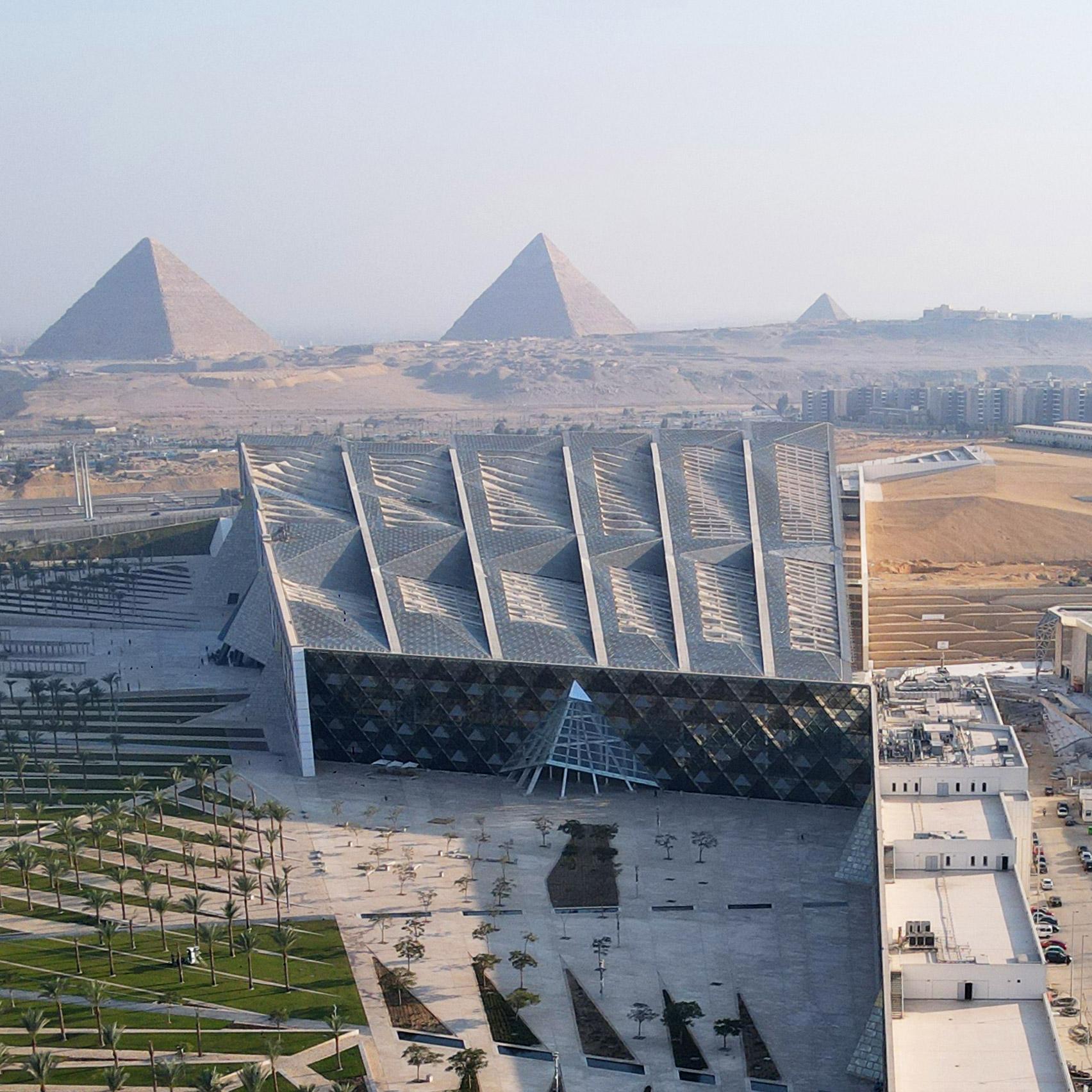 Aerial view of the Grand Egyptian Museum with the three Giza Pyramids rising behind it