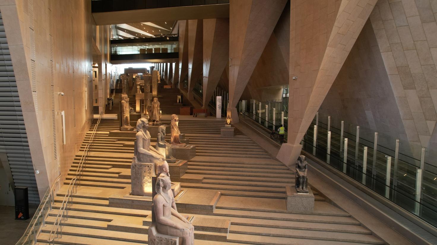 Ancient Egyptian statues line the sweeping grand staircase inside the NMEC museum atrium