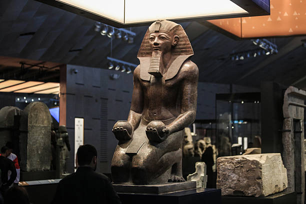 Large ancient Egyptian pharaoh statue displayed under spotlights in the NMEC gallery