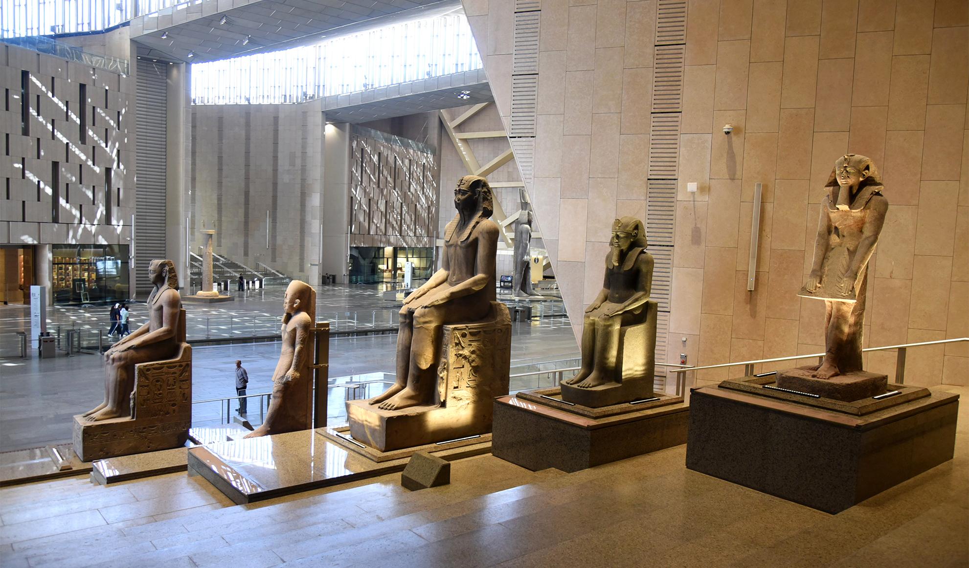 Row of large ancient Egyptian pharaoh statues displayed in NMEC's modern atrium hall