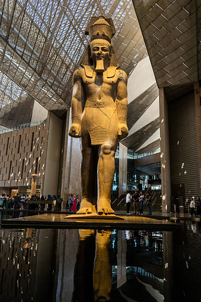 Colossal ancient Egyptian statue of Ramesses II reflected in a pool inside NMEC atrium