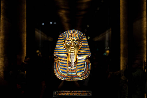 The iconic golden death mask of Pharaoh Tutankhamun displayed in a darkened museum case.