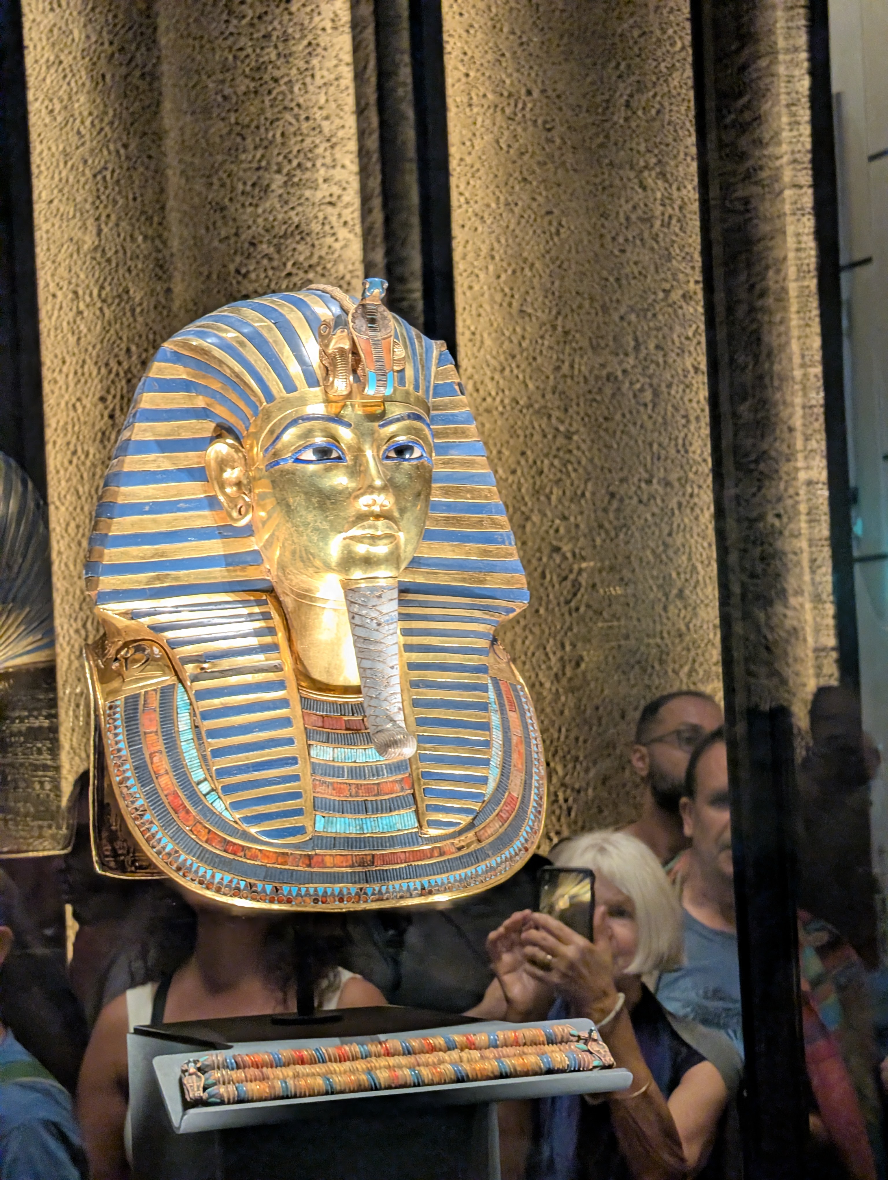 The iconic golden death mask of Tutankhamun on display, with museum visitors photographing it