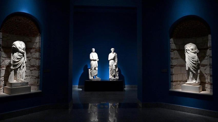 Roman togate marble statues displayed in niches of a blue-lit vaulted gallery
