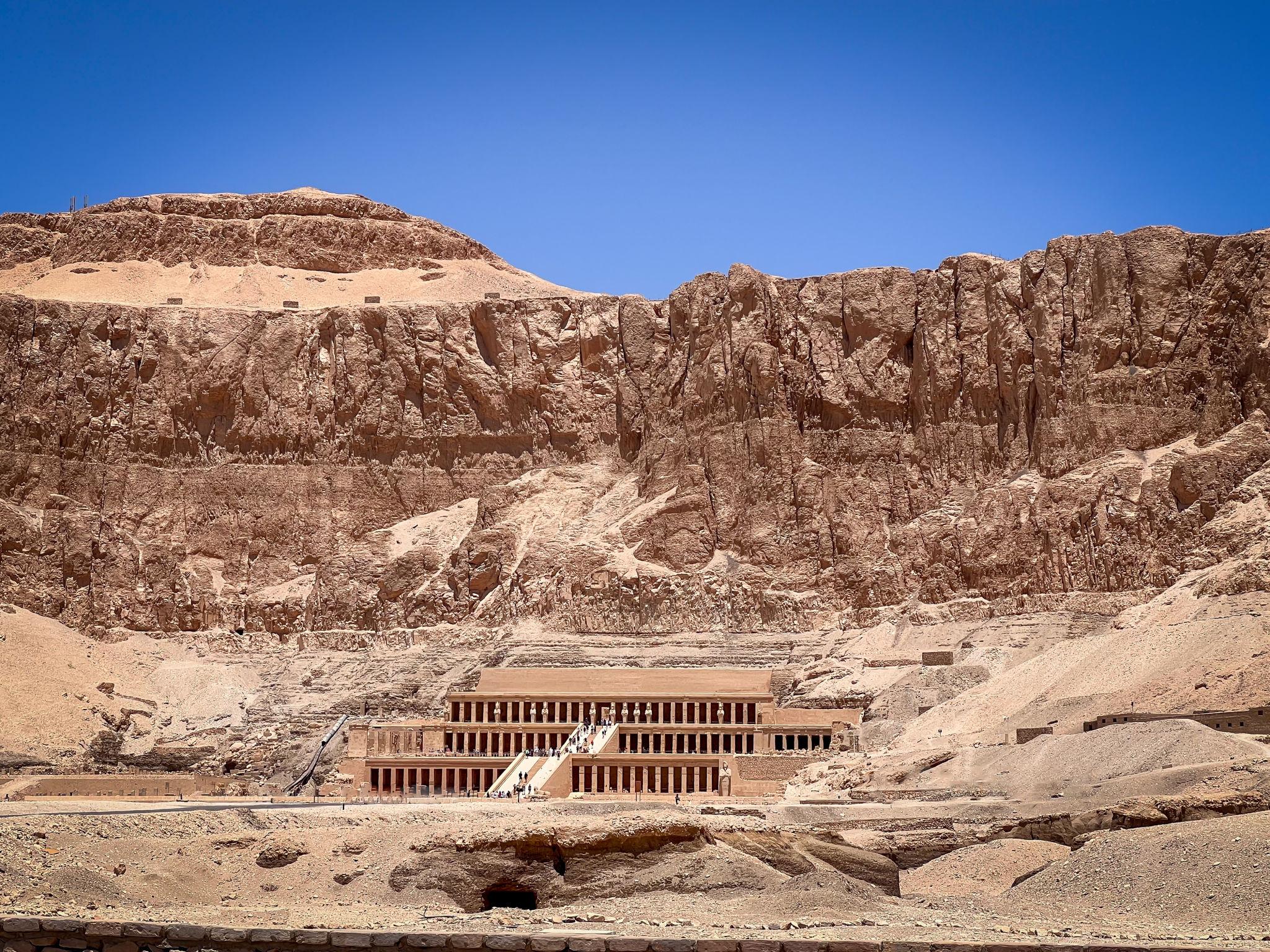 Distant view of Hatshepsut Temple nestled beneath towering Theban cliffs